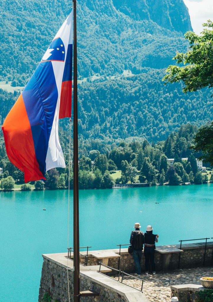 Slovenska zastava, ki plapola pred gozdnatimi griči